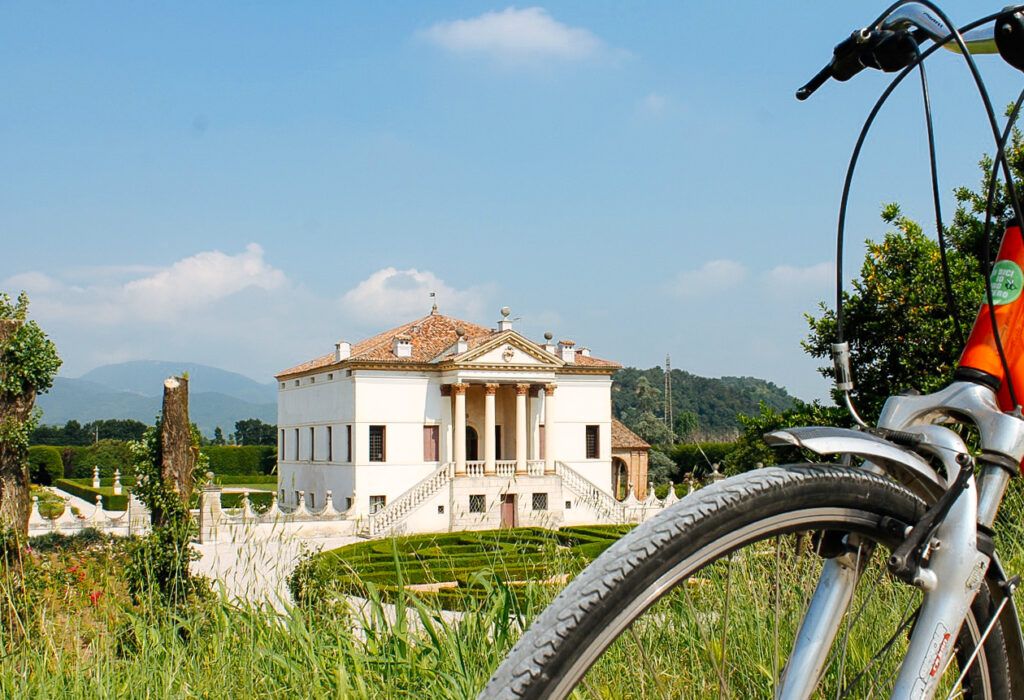 Villa con giardino e alberi sotto un cielo azzurro, bici in primo piano